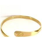 Gold cuff bracelet with paw print centerpiece and engraved inner text