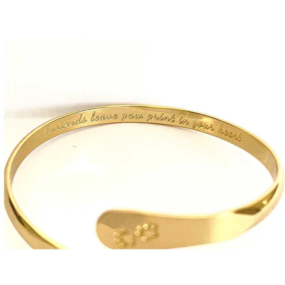 Gold cuff bracelet with paw print centerpiece and engraved inner text