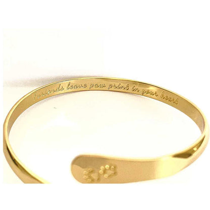 Gold cuff bracelet with paw print centerpiece and engraved inner text