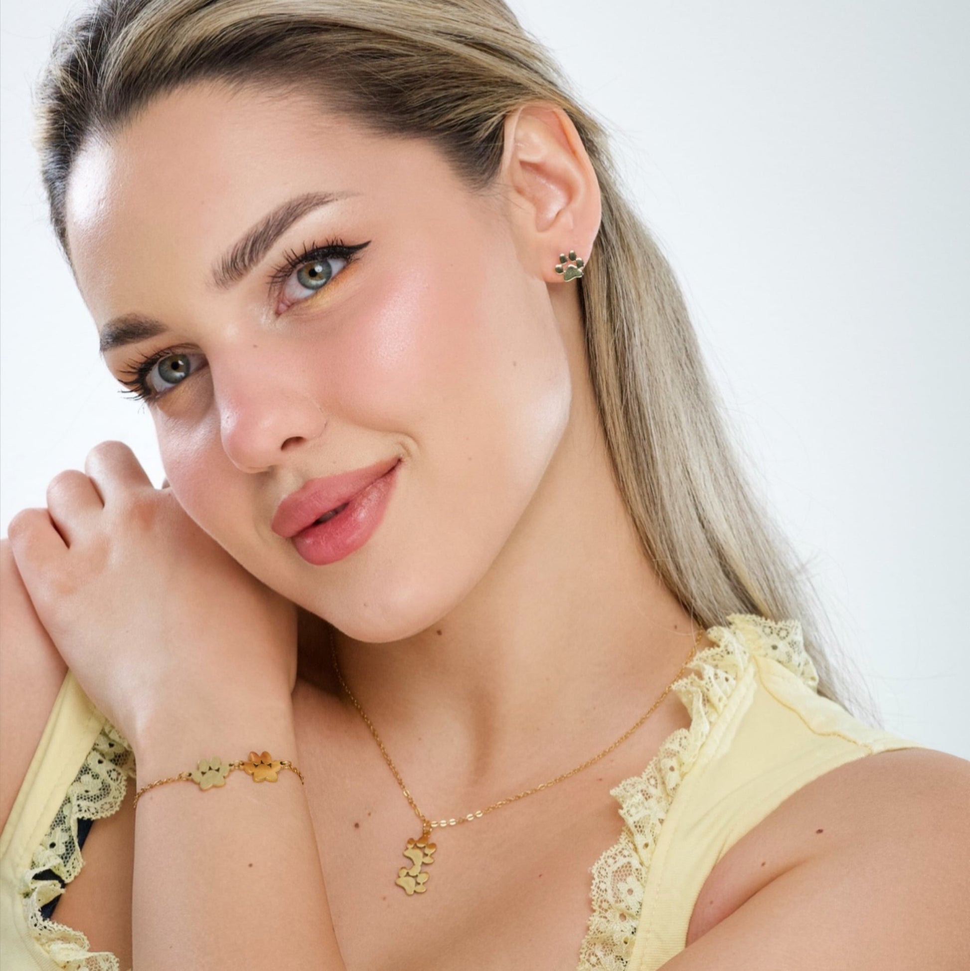 Gold paw print stud earrings on ear, small paw pad and toe-circle details