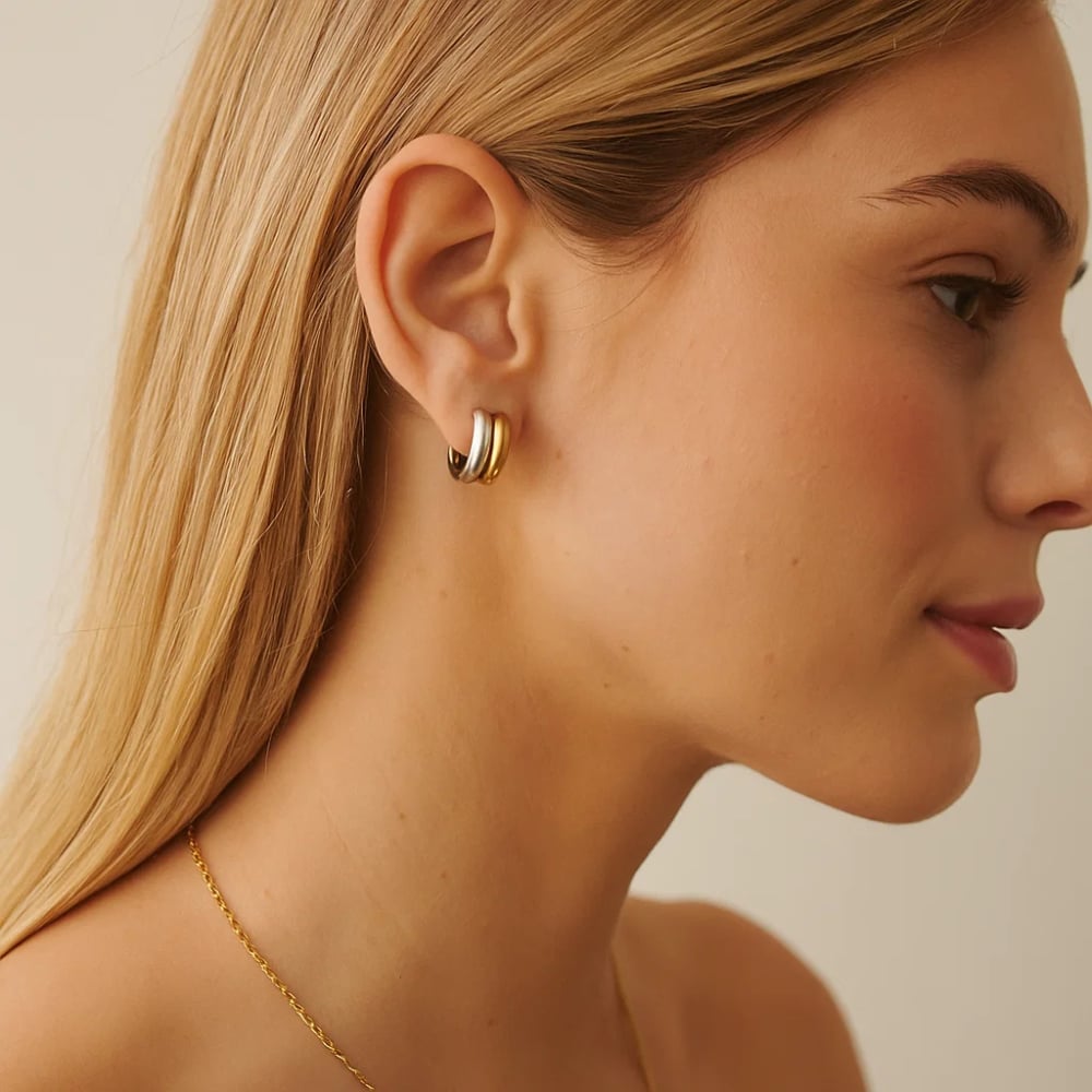Gold and silver sculptural hoop earring on ear with small stud post