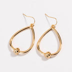 Gold teardrop hoop earrings with love-knot charm at the bottom