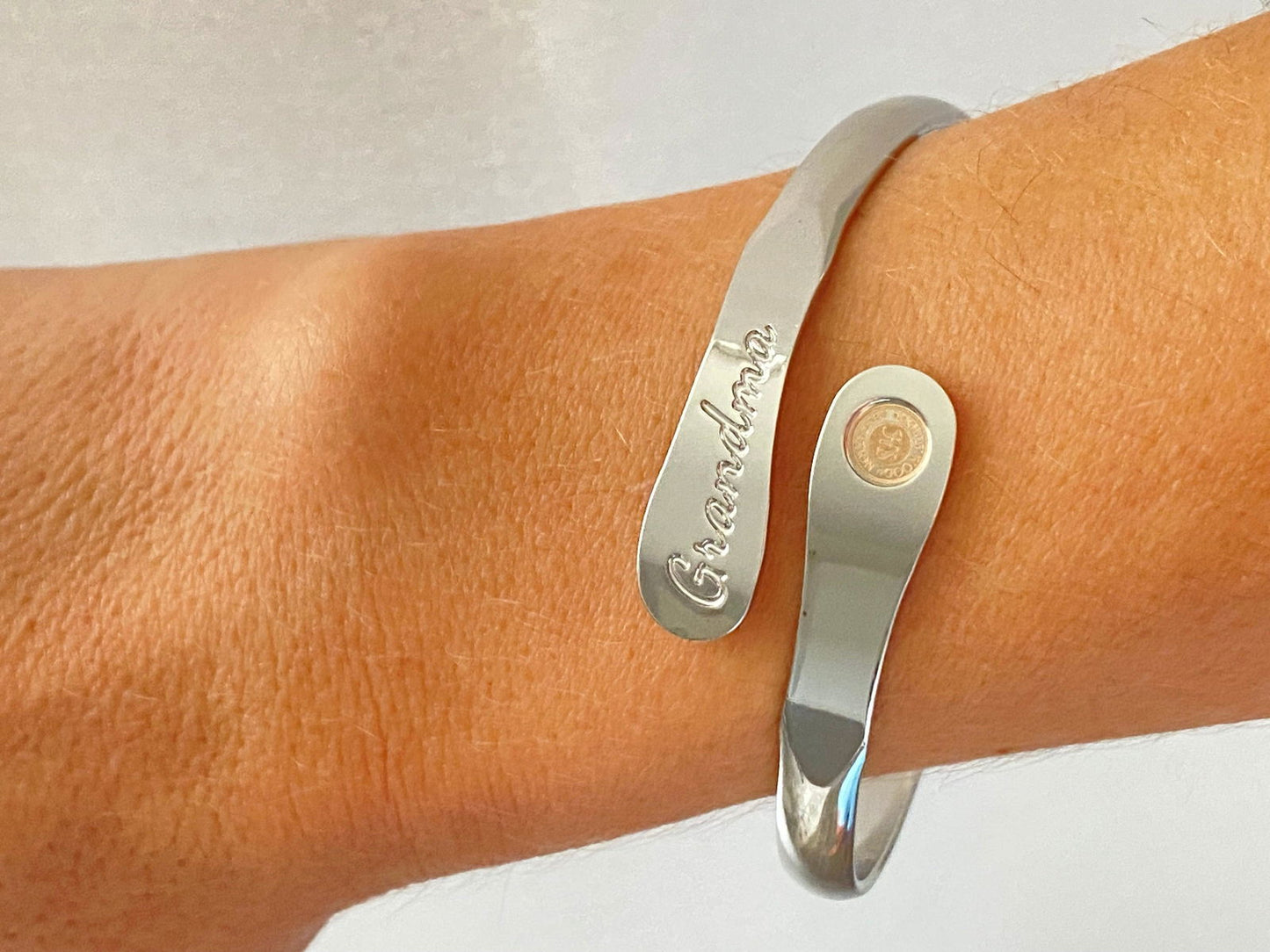 Silver-tone cuff bracelet with 'Grandma' script and round coin charm on wrist