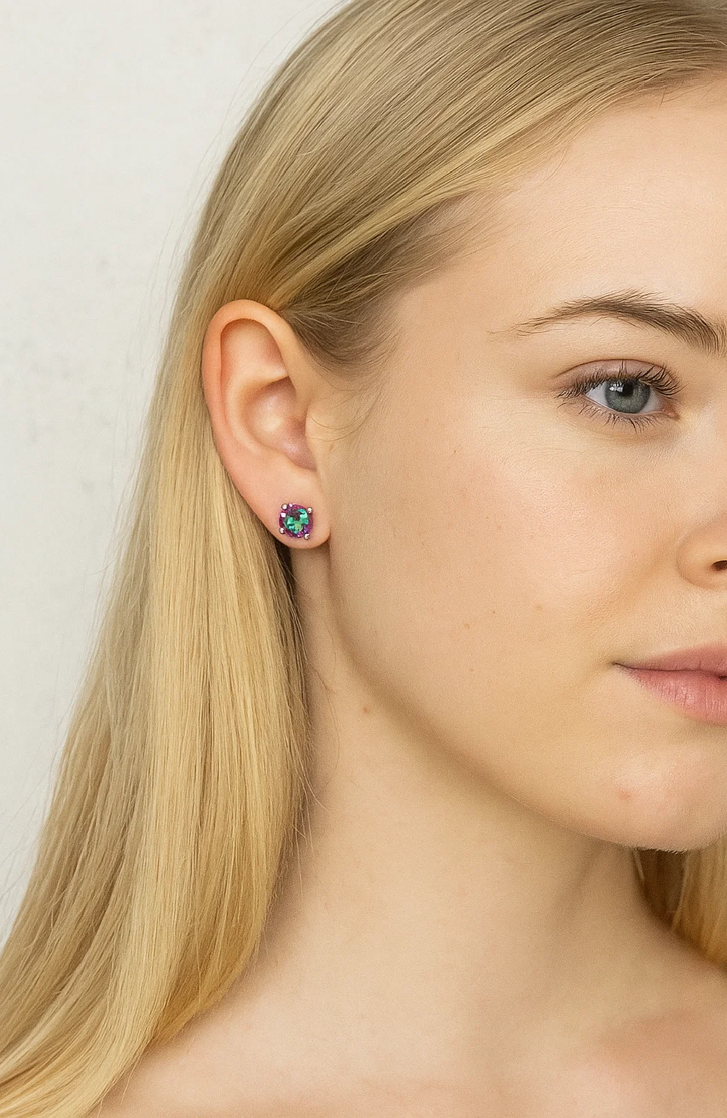 Round prong-set rainbow gemstone stud earrings on ear, small silver-tone prongs
