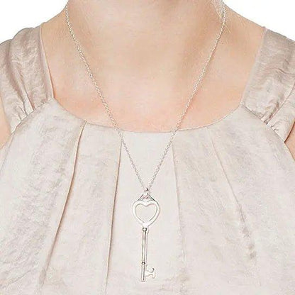 Heart and key pendant necklace worn on a light blouse with gathered neckline