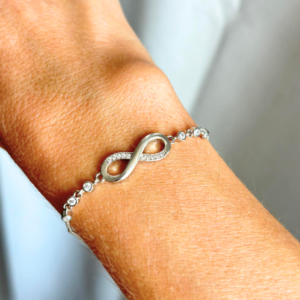 Silver infinity bracelet with small clear stones on a wrist