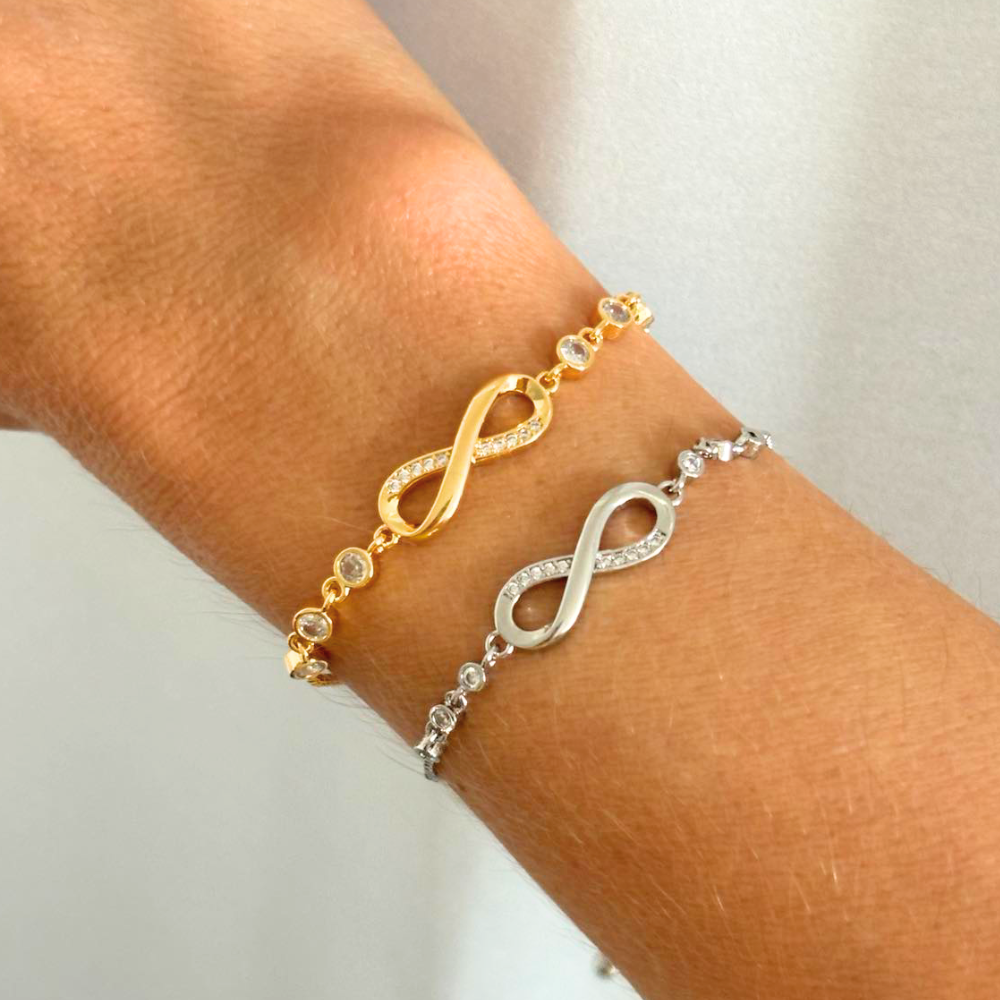 Gold and silver infinity bracelets on wrist with crystal bead chains and infinity charms