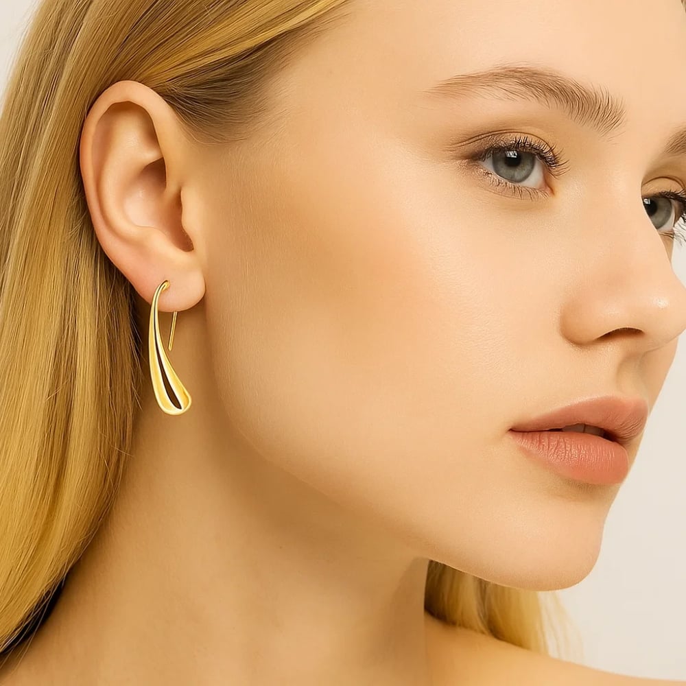 Gold teardrop dome drop earrings worn by model, curved profile, polished metal