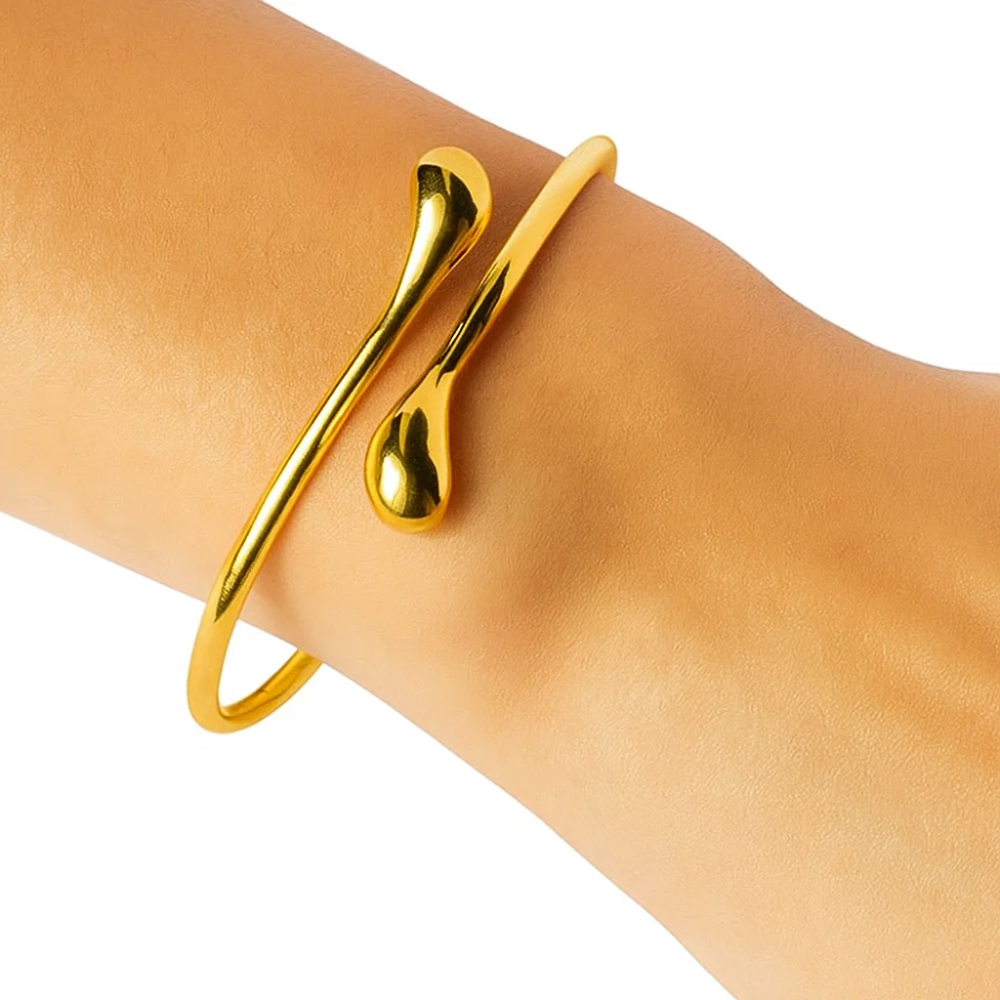 Gold teardrop open wrap bangle bracelet on wrist with raised teardrop accent
