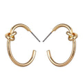 Gold knot hoop earrings with twisted knot at top of each rounded hoop