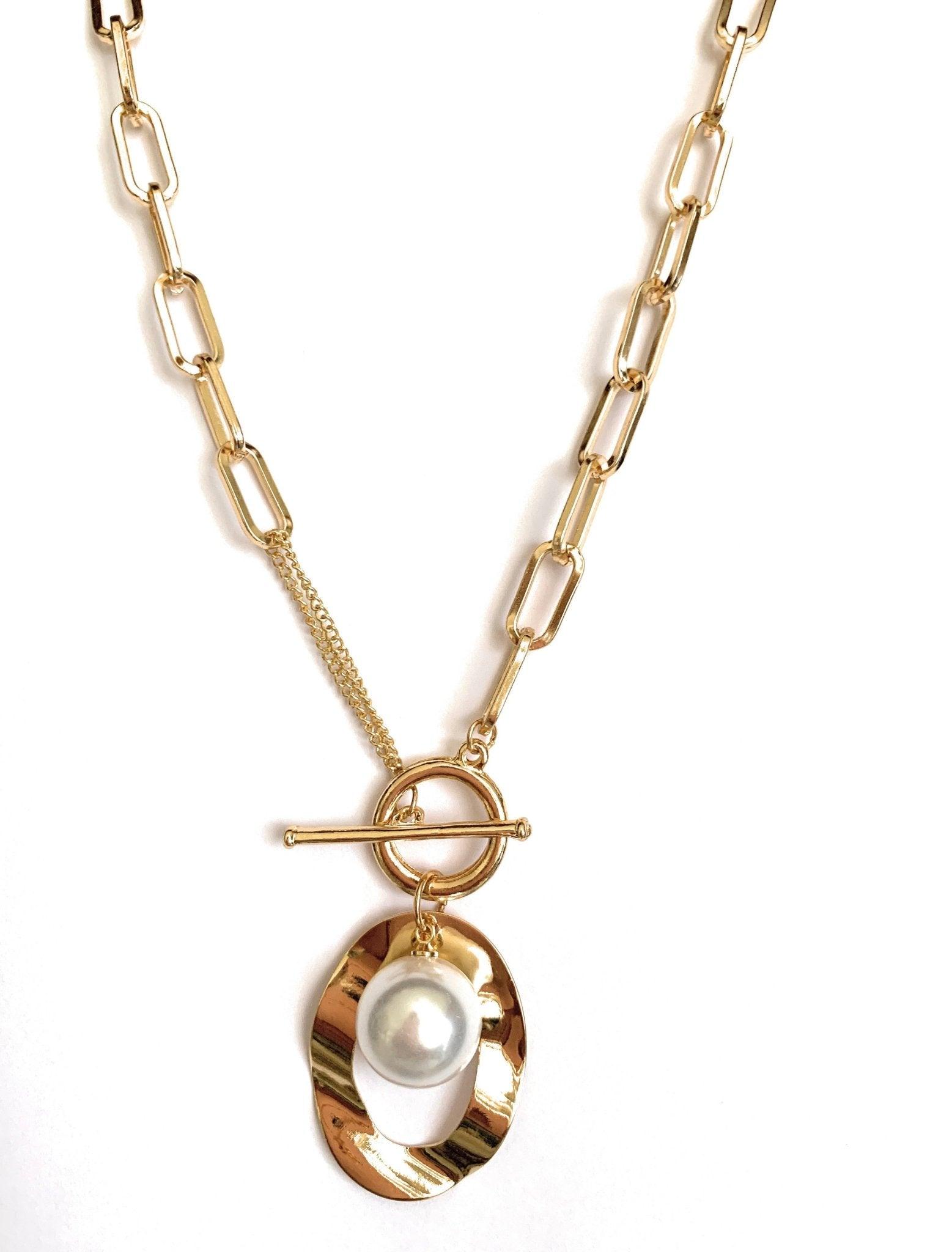 Gold chain necklace detail with curved pendant, faux pearl, and toggle clasp
