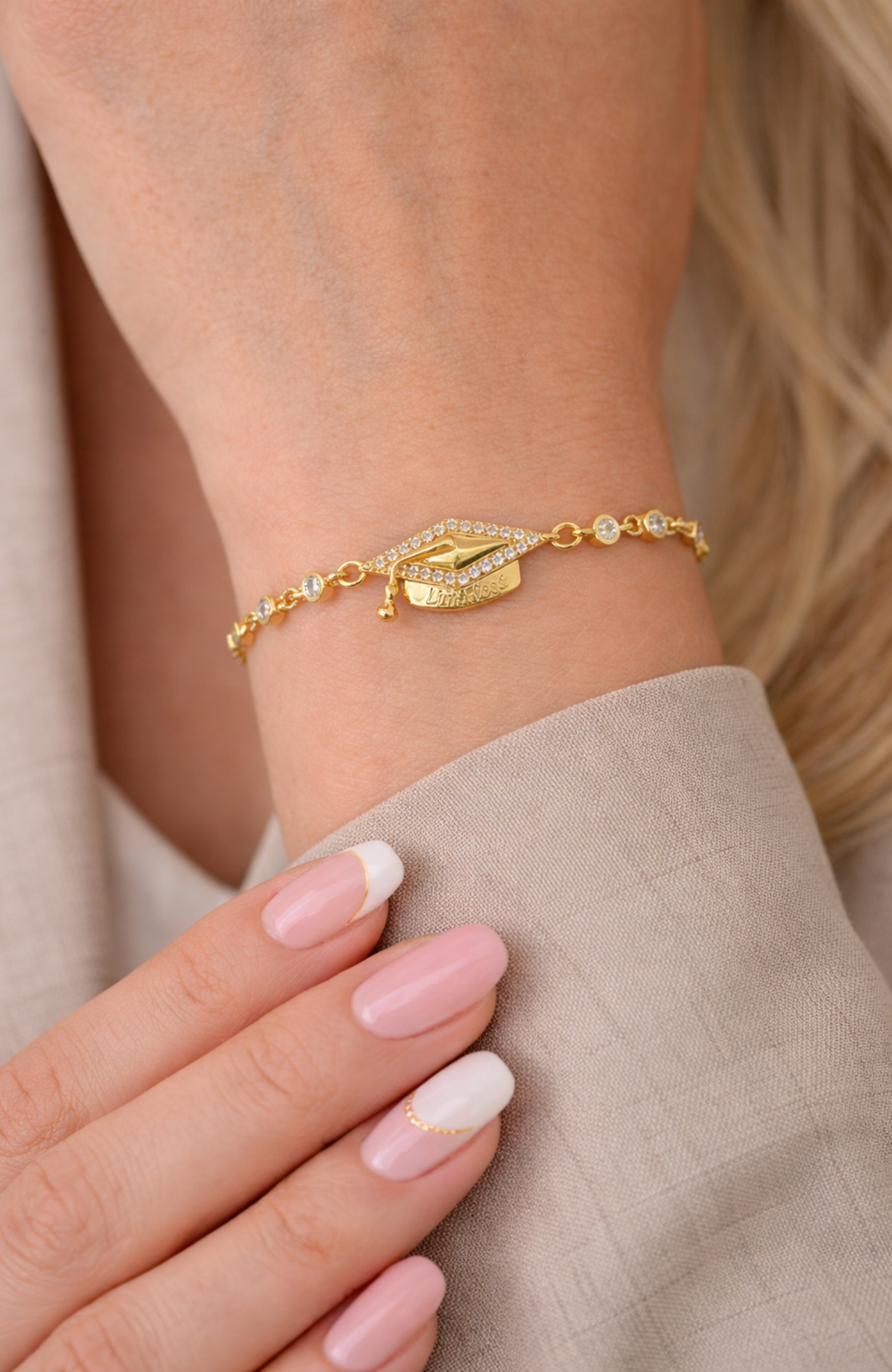 Gold adjustable pavé graduation cap bracelet on wrist