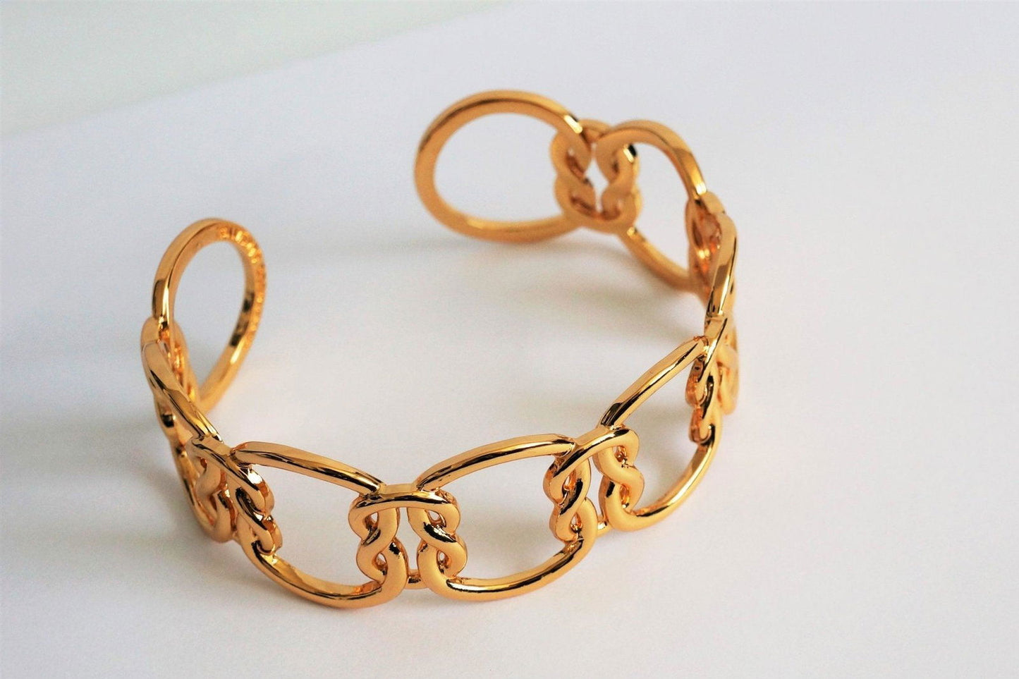 Gold chain love-knot bracelet with interlocking ring links and clasp detail