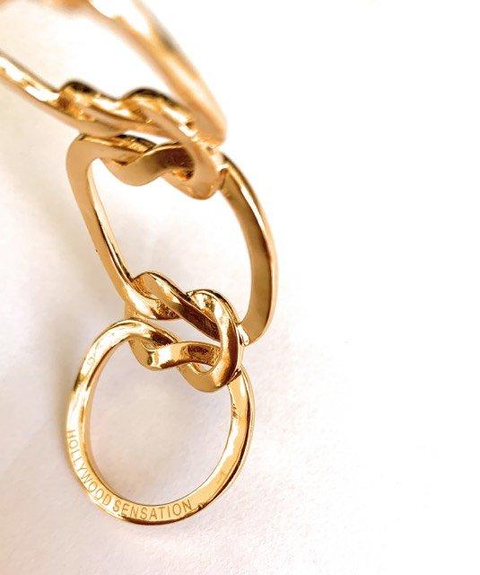 Gold love-knot bracelet close-up with oval charm tag on link chain