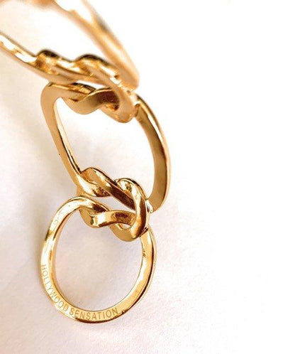Gold love-knot bracelet close-up with oval charm tag on link chain