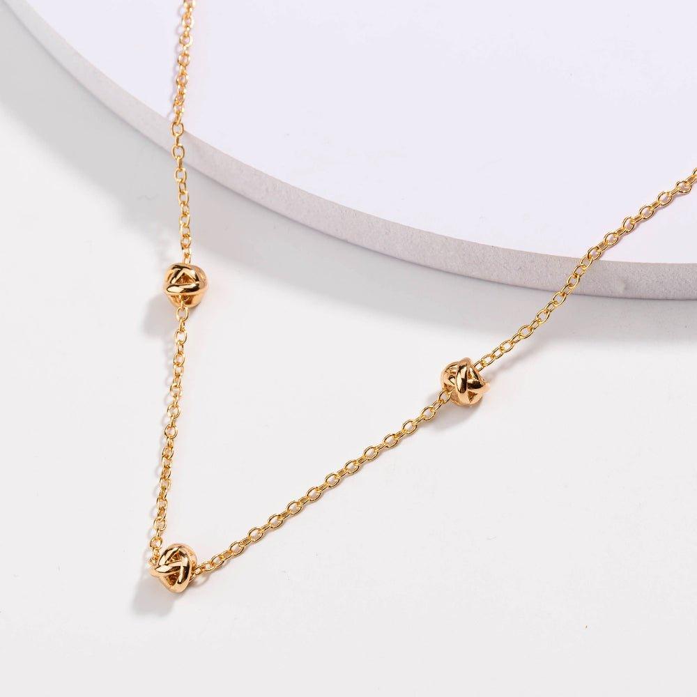 Gold-tone chain necklace with love-knot clasp and small knot pendants