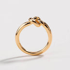 Gold love knot commitment ring with raised knot element, glossy shine