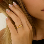 Gold love-knot ring on finger with twisted knot design, polished band