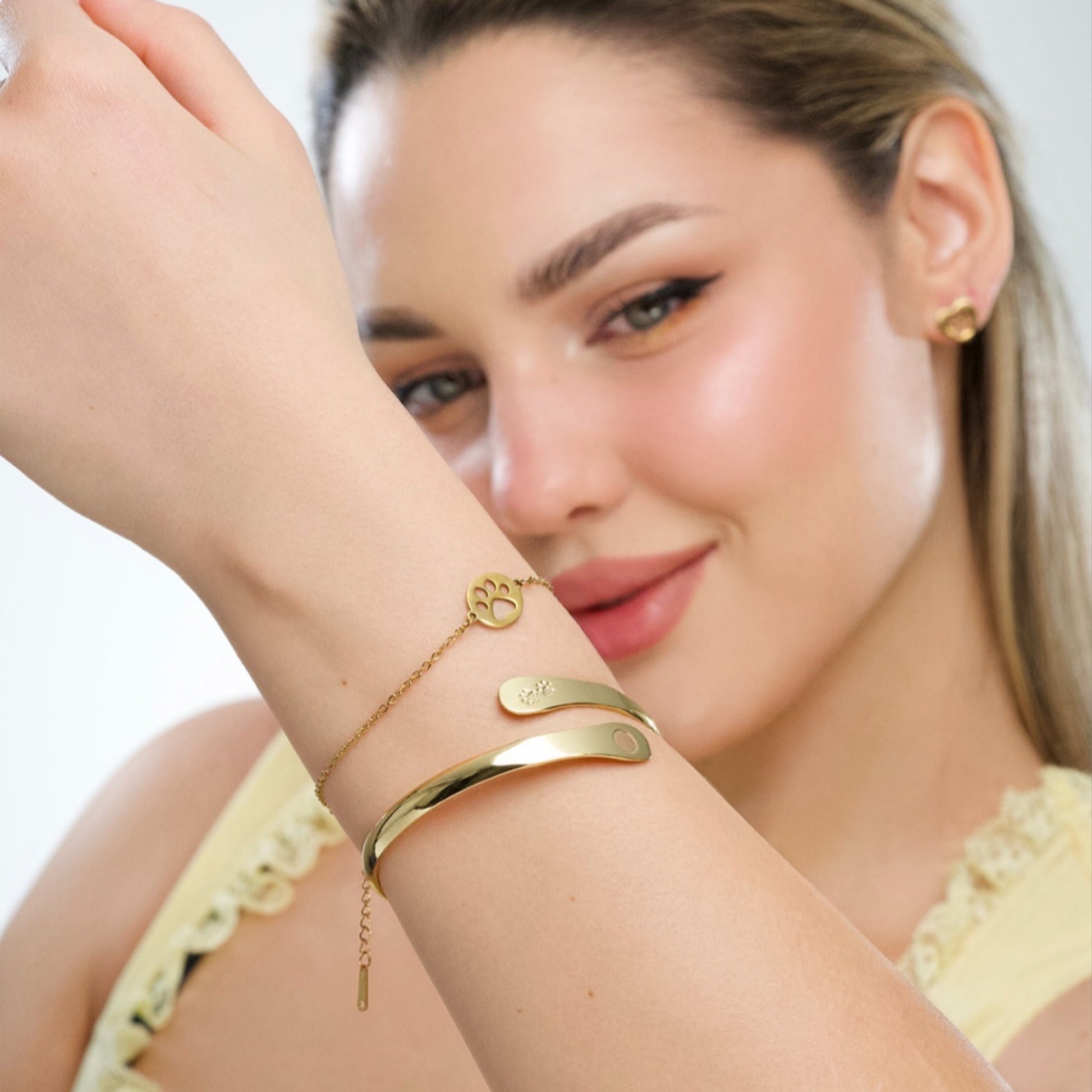 Gold-tone paw charm bracelet on wrist with chain links