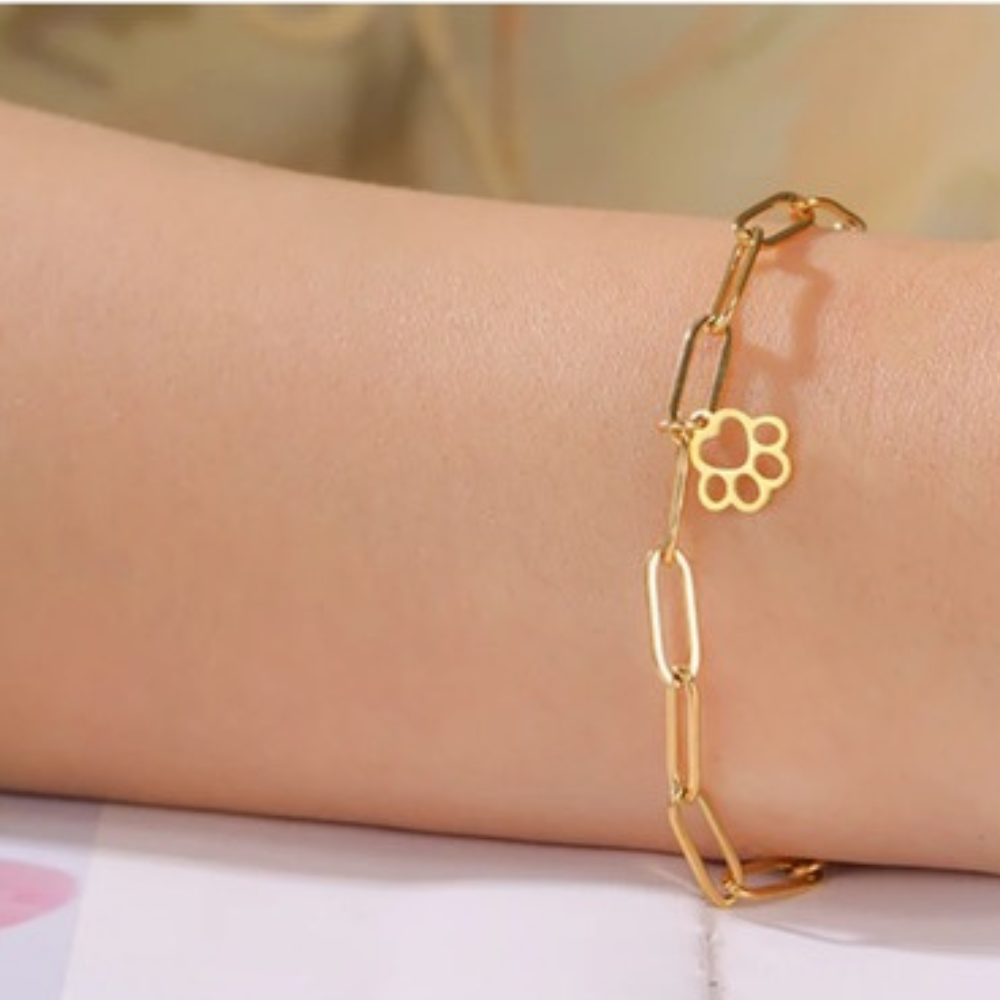 Gold paw-print link bracelet worn on wrist with round paw charm