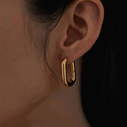 Gold rectangular hoop earring on model ear, close-up