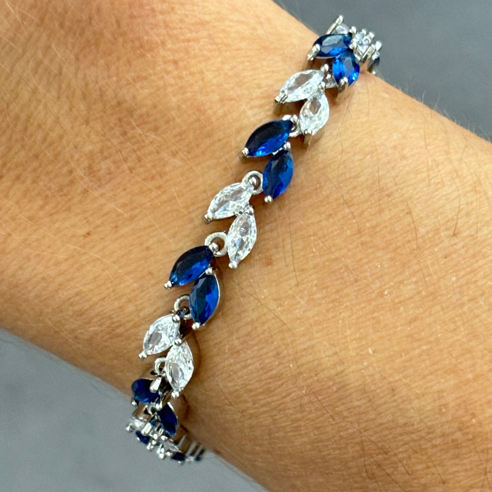 Silver tennis bracelet on wrist featuring blue marquise stones and clear cubic zirconia links