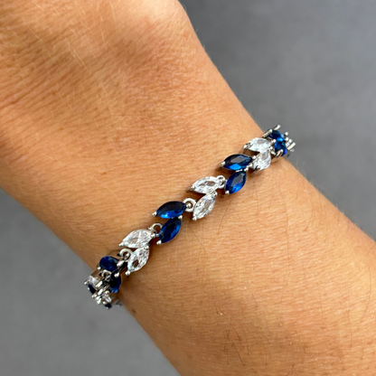 Silver tennis bracelet on wrist with blue marquise stones and clear cubic zirconia accents