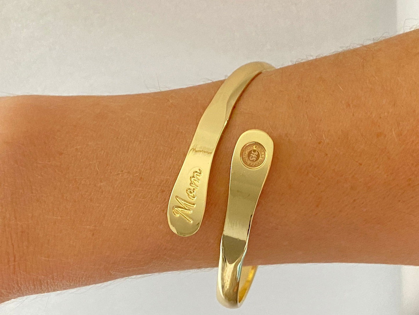 Gold-tone engraved mom cuff bracelet on arm with round side emblem