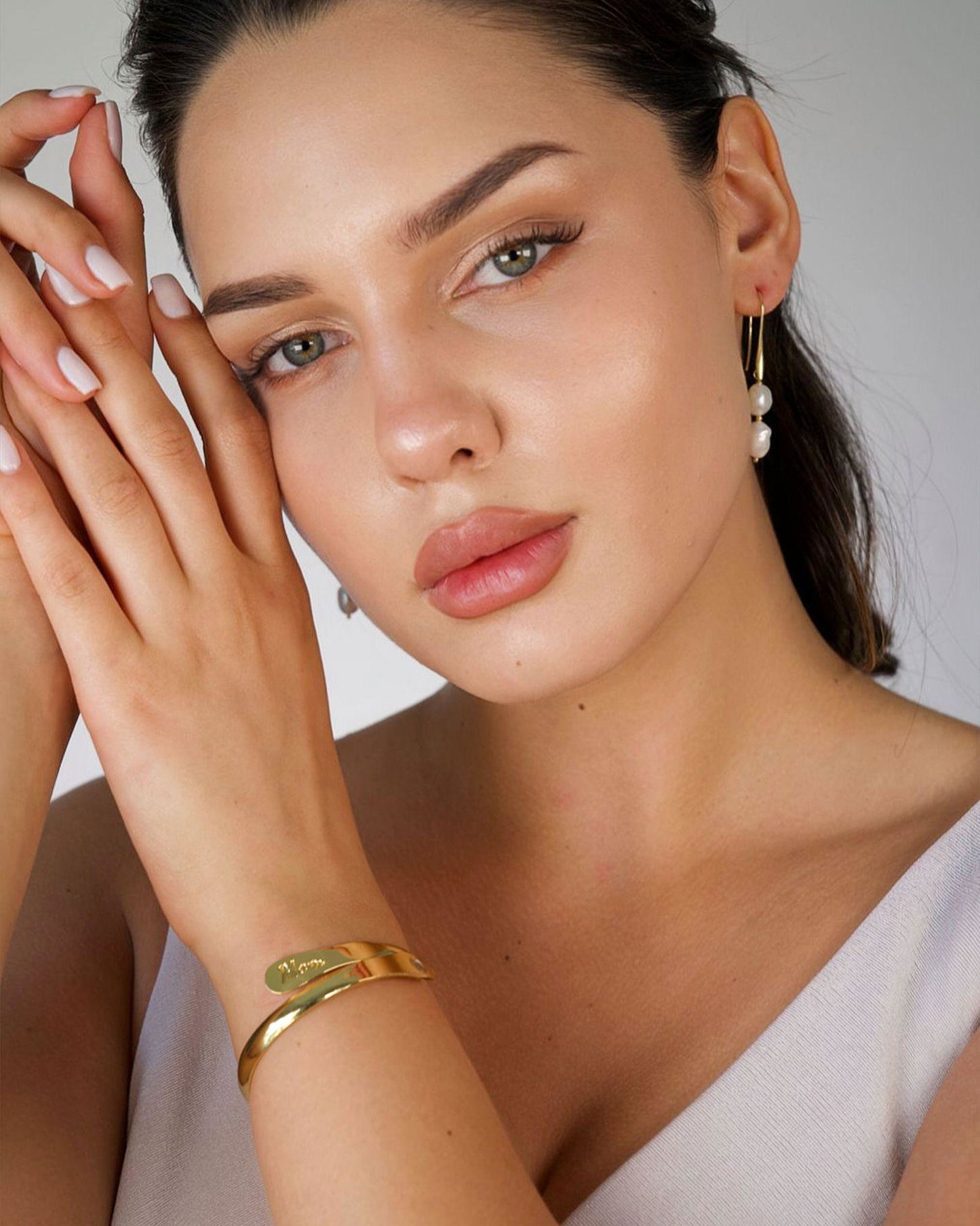 Gold-tone engraved mom cuff bracelet on wrist with script “Mom”