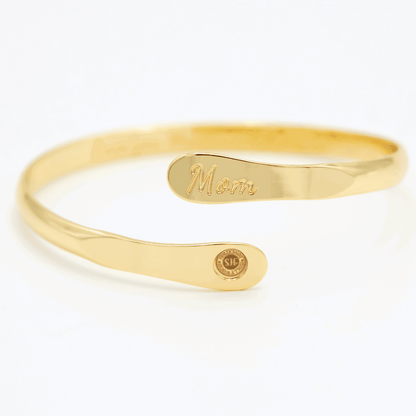 Gold mom bangle bracelet with oval “Mom” engraving and circular charm end