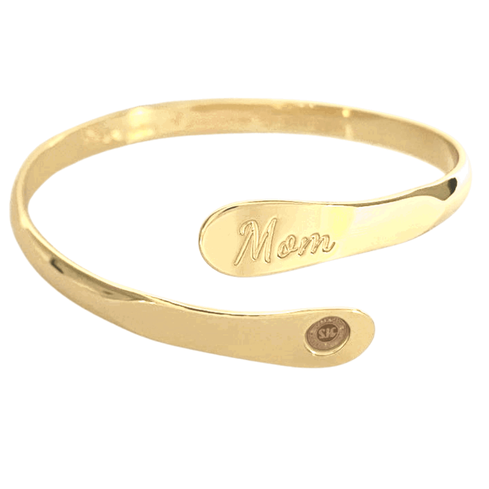 Gold mom bangle bracelet with oval “Mom” engraving and small round emblem near the end
