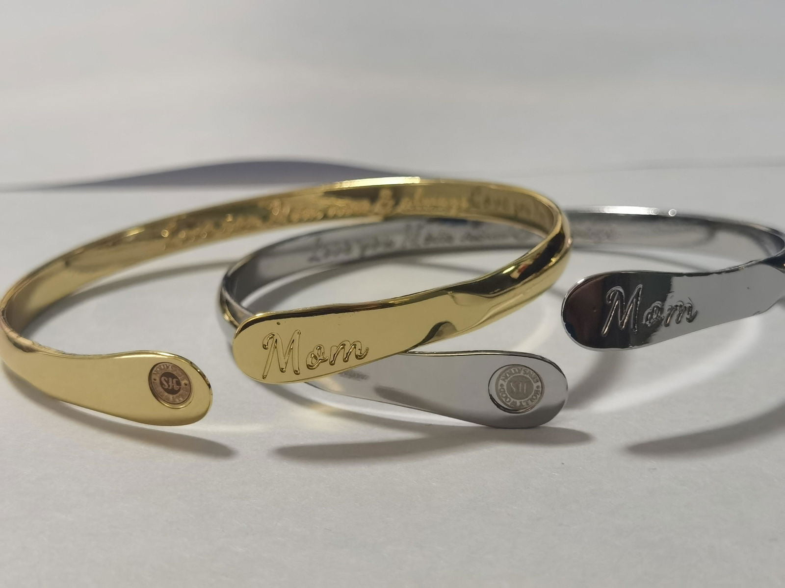 Set of gold and silver mom bangle bracelets with oval “Mom” engravings and round emblems
