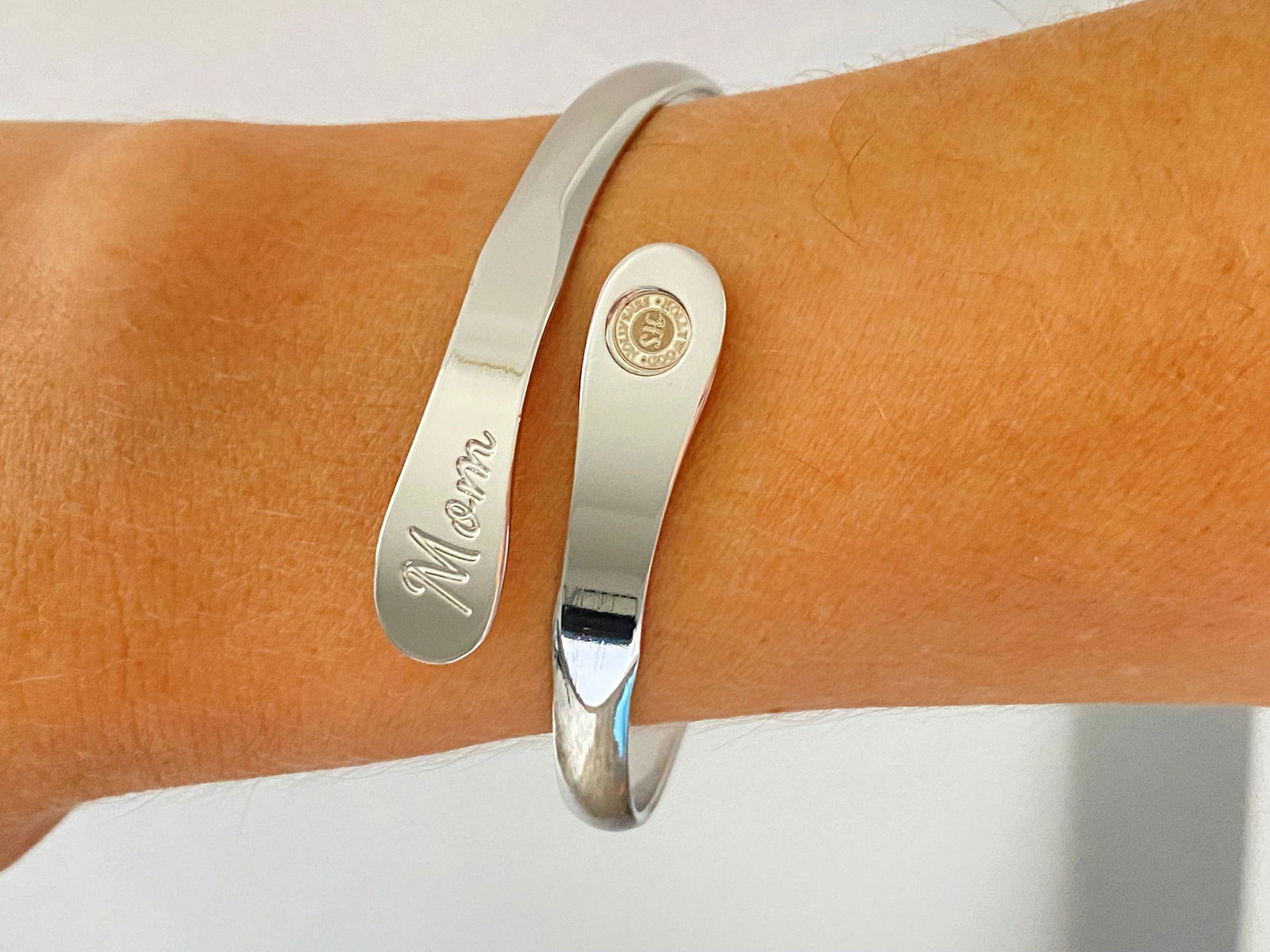Silver-tone engraved mom cuff bracelet on arm with script “Mom” side