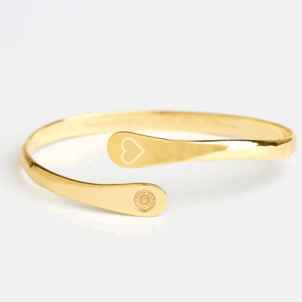 Gold cuff bracelet with engraved heart motif and round logo charm