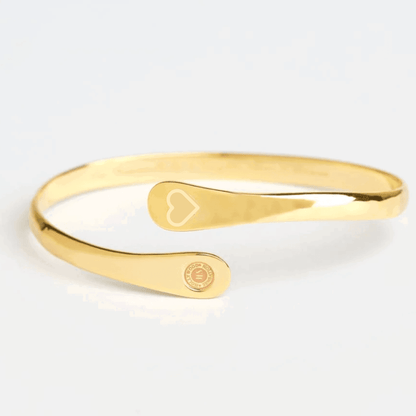 Gold cuff bracelet with engraved heart motif and round logo charm