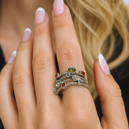 Silver-tone multicolor gemstone ring on hand with green, gold, and clear stones