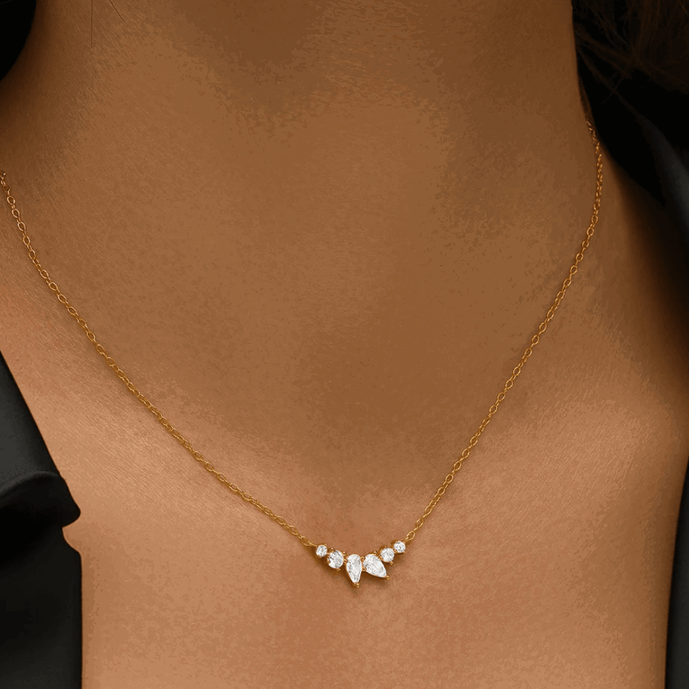 Gold-tone necklace with pear-shaped and round-cut cubic zirconia cluster, close-up