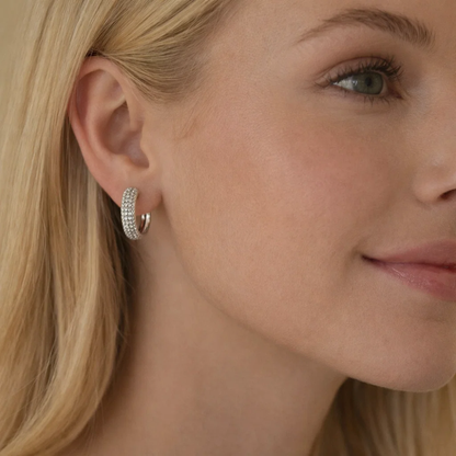 Pavé huggie hoop earrings in silver on model's ear