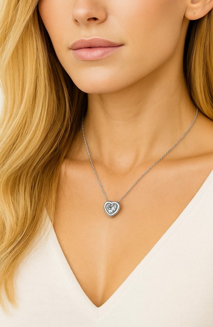 A woman with long blonde hair wears a V-neck white top and the Heart Necklace Cubic Zirconia Crystal, a white gold plated necklace featuring a sparkling cubic zirconia center.