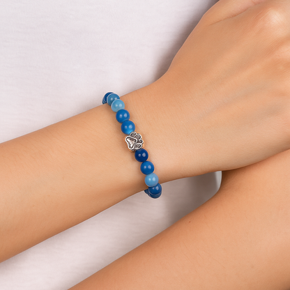Blue bead charm bracelet on arm with paw print metal charm