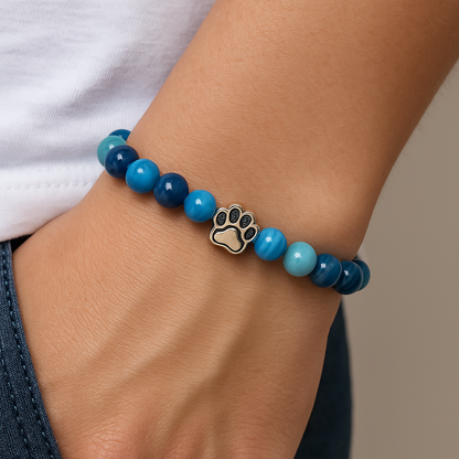 Blue bead charm bracelet on wrist with paw print metal charm detail