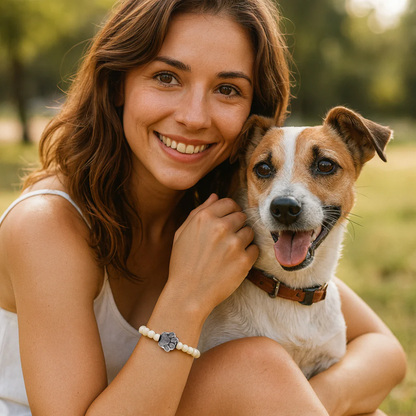 Wrist-worn paw print charm bracelet with white beads on model holding a dog