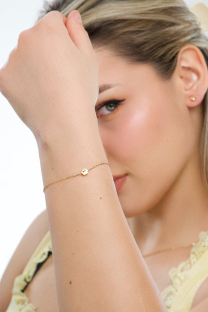Gold mini paw print stud earrings on model’s ear