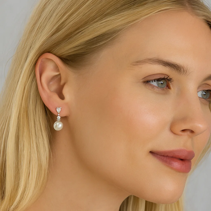 Pearl drop earrings with cubic zirconia accents and silver-tone setting on model