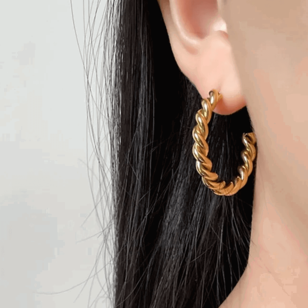 Large gold twisted rope hoop earring on ear