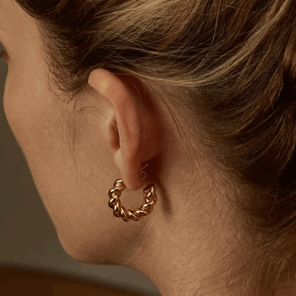Gold twisted rope hoop earring with hinged clasp visible at ear