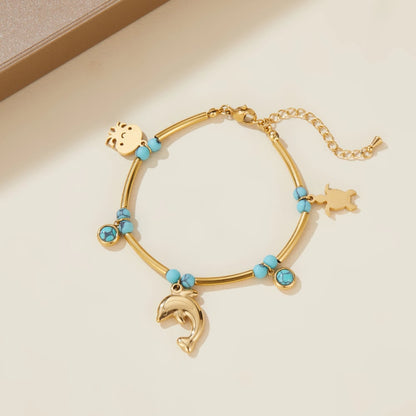 Gold-tone bangle bracelet with turquoise beads and dolphin charm, flat animal head charm