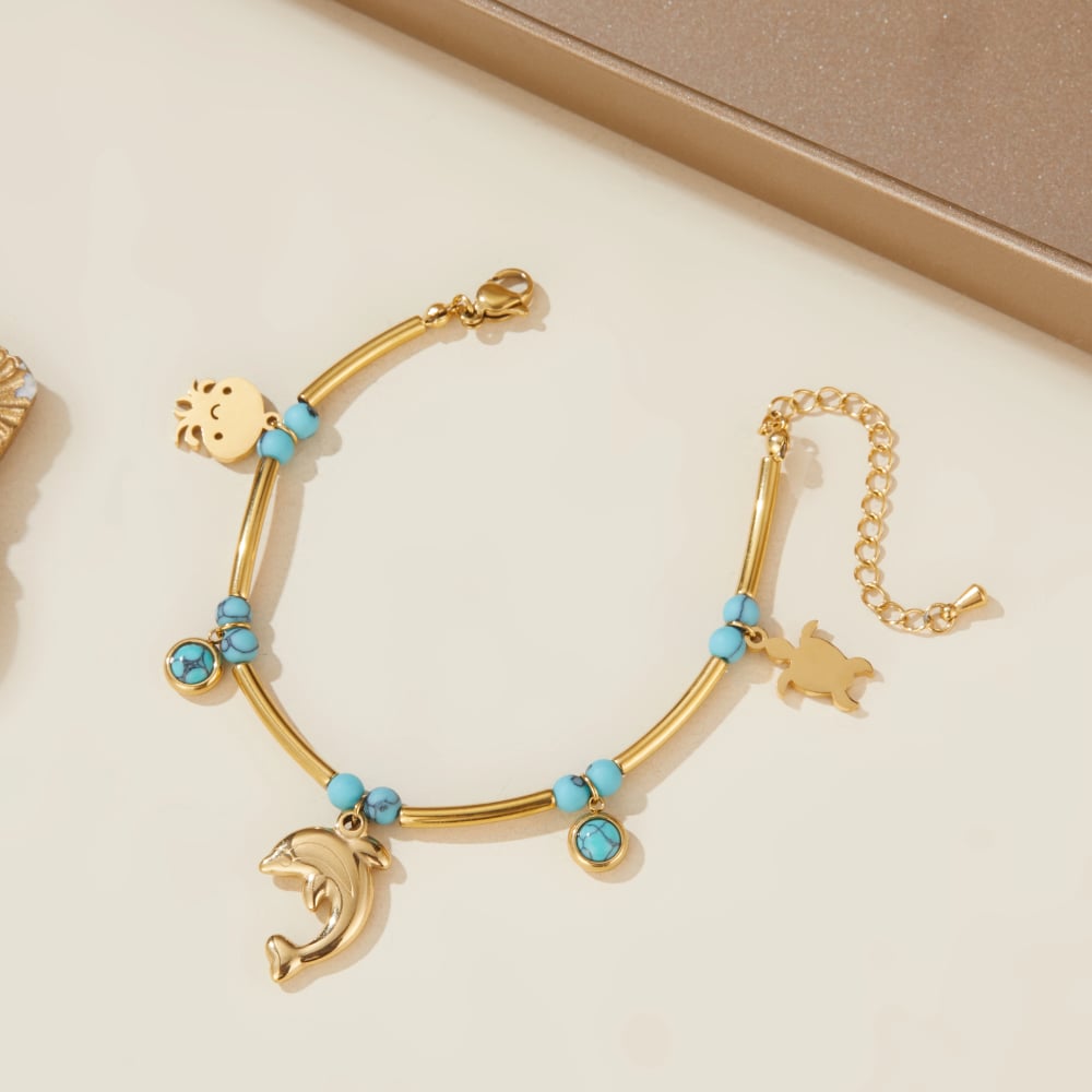 Gold-tone turquoise charm bracelet with dolphin drop charm and multiple round bead accents