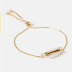 Gold seashell charm bracelet close-up with oval shell centerpiece and spring clasp.