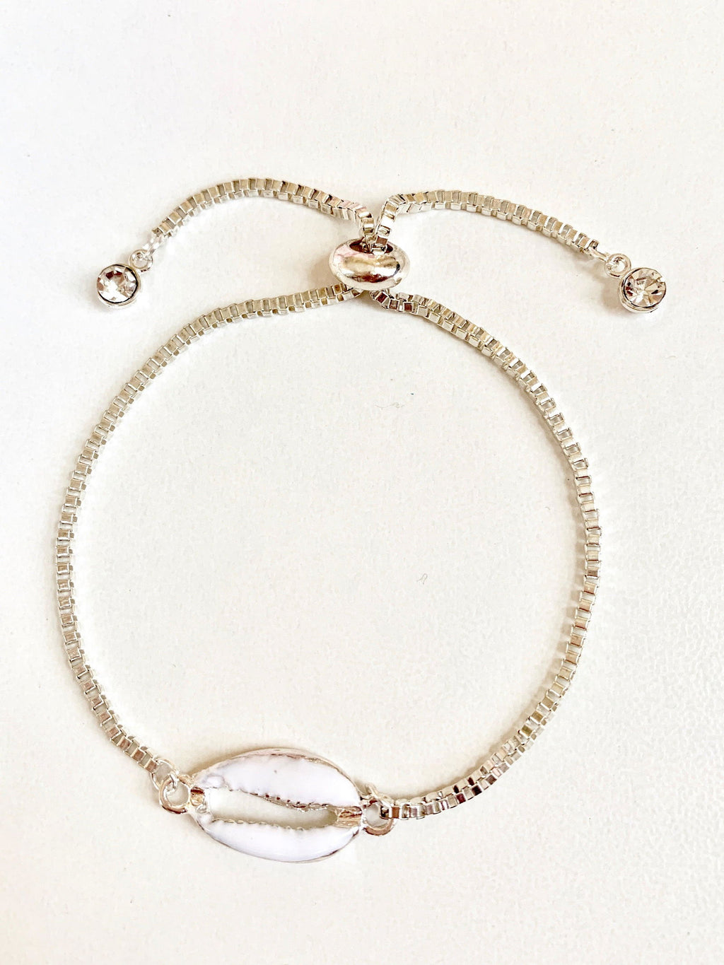 Silver seashell charm bracelet with spring clasp and small round crystal accents.